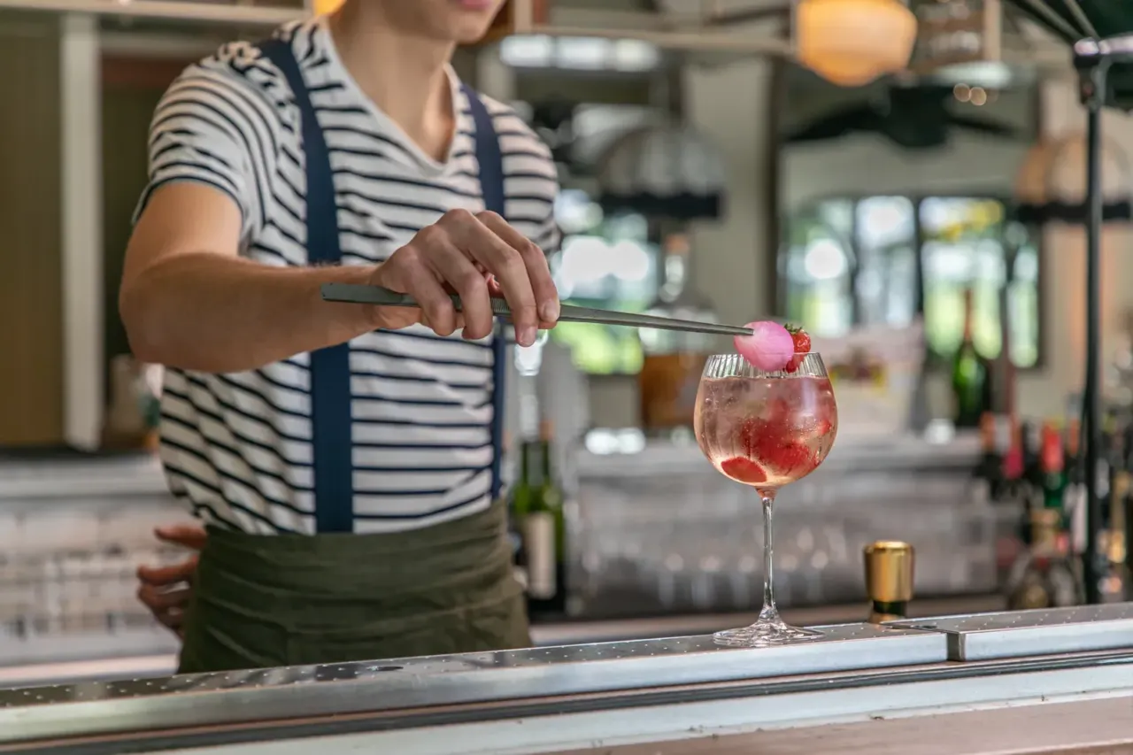 Barman prépare une boisson avec fraises et glace.