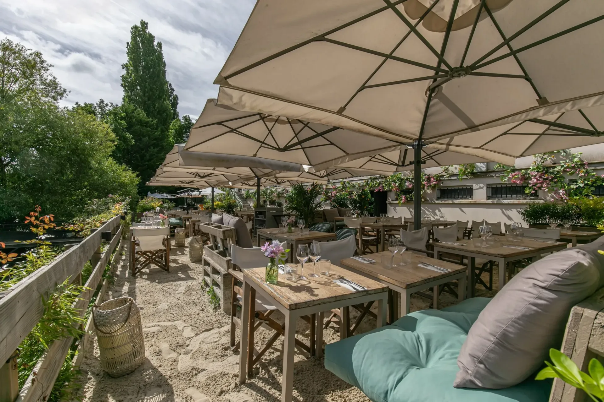 Terrasse de restaurant avec parasols et verdure luxuriante.
